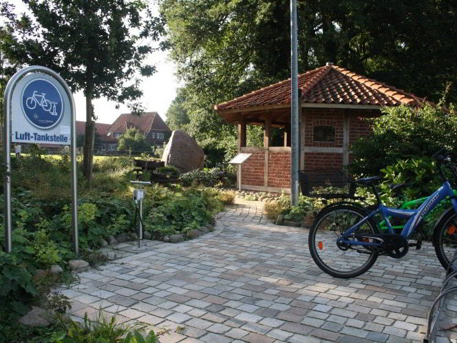 Ein Hinweisschild mit der Aufschrift "Lufttankstelle". Daneben ein Fahrrad in einem Fahrradständer.